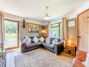 a living room with a leather couch and a window at Egmont Farmhouse in Newenden