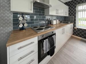 a kitchen with white cabinets and a stove top oven at Poplar Zareba in Anderby