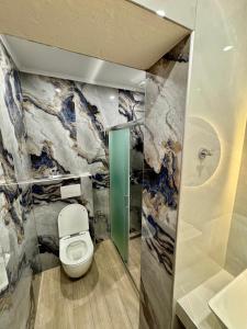 a bathroom with a toilet and a marble wall at Hotel Filoxenia in Ligia