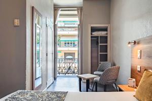 a room with a bed and a table and chairs at Hôtel Helvétique in Nice