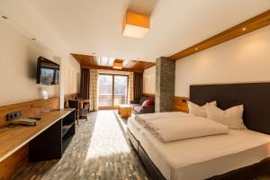 a bedroom with a bed and a desk with a television at Hotel Mozart in Landeck