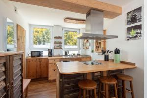 a kitchen with wooden cabinets and a island with bar stools at Apartment Lichterfunkeln für junge Paare mit Panorama-Seeblick in Daisendorf