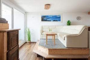 a living room with a white couch and a table at Apartment Lichterfunkeln für junge Paare mit Panorama-Seeblick in Daisendorf