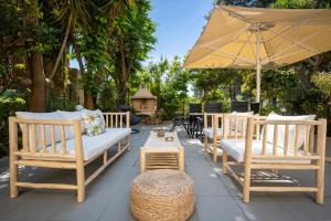 a group of chairs and an umbrella on a patio at Almyra Living - Adults Only in Agios Gordios
