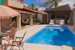 a swimming pool with chairs and a hammock next to a house at Pousada Residência Lençóis in Barreirinhas