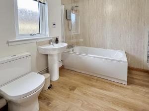 a white bathroom with a toilet and a sink at Fern Cottage - Uk5868 in Achmelvich