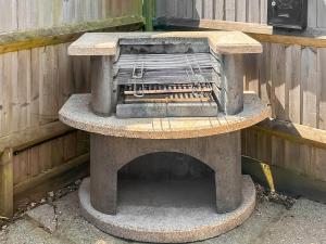 a stone oven sitting next to a wooden fence at The Lodge in Northiam