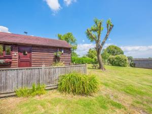 a wooden house with a fence and a yard at The Lodge in Northiam +13 photos