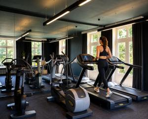 a woman running on a treadmill in a gym at Auberge du Pêcheur in Sint-Martens-Latem