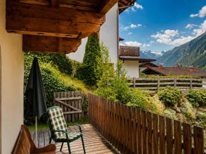 a wooden deck with a chair and an umbrella at Haus Alpenkönig Exclusive Apartments near Stubai Glacier in Neustift im Stubaital