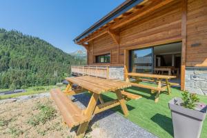 a picnic table and bench outside of a log cabin at Chalet APY - Grand chalet neuf avec terrasse, 6 chambres en-suite , wifi, balcon, etc in Les Gets