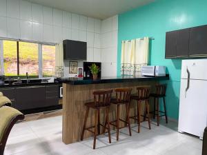 a kitchen with a counter with stools and a refrigerator at Casa do Lago - Casa de Campo em Campina Grande do Sul in Campina Grande do Sul