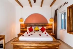 a bedroom with a bed with red and yellow pillows at African Bungalows in Nungwi