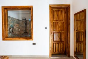 a mirror on a wall next to a door at African Bungalows in Nungwi