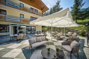 a patio with chairs and tables and an umbrella at Hotel Bärenbachhof in Saalbach-Hinterglemm