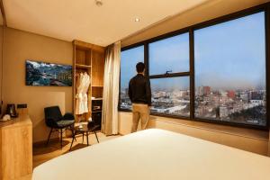 a man looking out of a large window in a bedroom at ADAY Hotel Casablanca in Casablanca