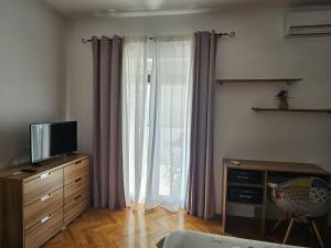 a living room with a tv and a window with curtains at Rooms Perina Tisno in Tisno