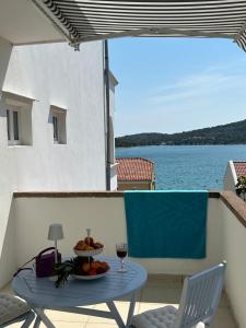a table with a bowl of fruit and a glass of wine at Rooms Perina Tisno in Tisno