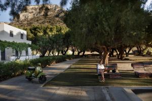 a man sitting on a park bench next to a scooter at Mazi in Sifnos in Sifnos
