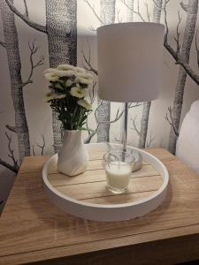 a table with a lamp and a glass of milk on it at Apartament BLASK Jeziora in Augustów