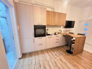 a kitchen with white cabinets and a desk with a table at Apartman Jana in Bar