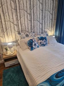 a bedroom with a bed with trees on the wall at Apartament BLASK Jeziora in Augustów