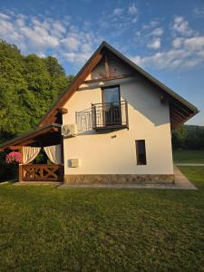 a house with a balcony and a grass field at Jagodowa Czulnia in Zwierzyń