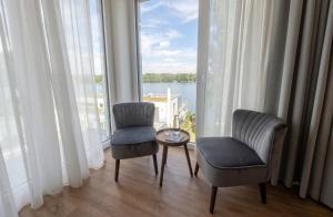 a room with two chairs and a table and a large window at H24 Hotel Berlin Grünau in Berlin