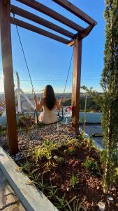 a woman sitting on a swing in a garden at Pousada Vista Chic in Cunha