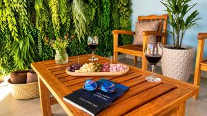 a wooden table with two glasses of wine and a tray of fruit at Pousada Vista Chic in Cunha