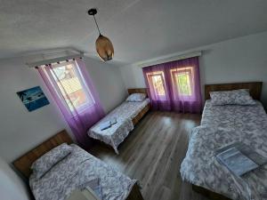 a room with two beds and two windows at Peja Riverside Hostel in Peje