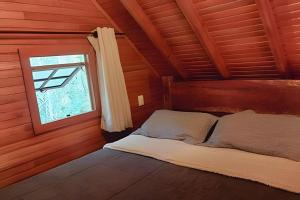 a bed in a wooden room with a window at Cabana Bem-te-vi in Três Coroas +32 photos