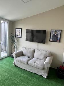 a living room with a white couch and a flat screen tv at Studio 156 in Boussu