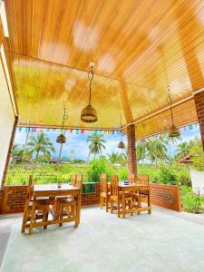 a dining room with wooden tables and chairs and a large window at Eleen Bungalow in Tetebatu