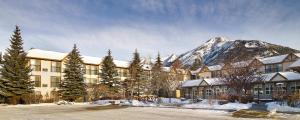 a building with a snow covered mountain in the background at Coast Canmore Hotel & Conference Centre in Canmore