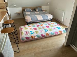 a bedroom with a bed with a flower blanket at La Pose Normande in La Cerlangue