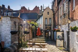 an alley with wooden benches and an umbrella at George & Pilgrims Hotel in Glastonbury