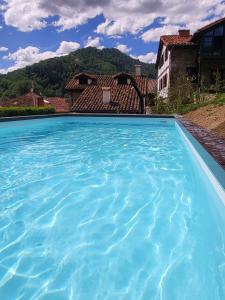 a pool of blue water with a house in the background at Explora Picos de Europa in Cosgaya