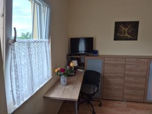 a room with a desk and a window with a vase of flowers at Sonniges Zimmer im Einfamilienhaus in Berlin