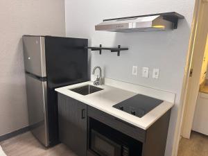 a kitchen with a sink and a refrigerator at Studio 6 Suites Jacksonville, NC - Camp LeJeune in Jacksonville