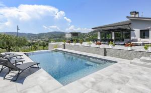 a swimming pool with two chairs and a house at Villa Casara Design and Relax Lago di Garda in Costermano