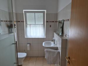 a bathroom with a sink and a toilet and a window at Sonniges Zimmer im Einfamilienhaus in Berlin