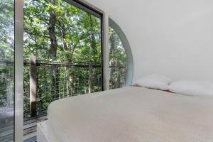 a bedroom with a bed and a large window at Cabane Le Module in Angoisse