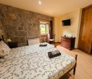 a bedroom with a bed and a stone wall at Casa da Bia - Gerês in Terras de Bouro