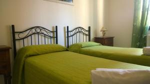two beds in a room with green sheets at B&B Salento Vacanze in Maglie