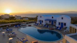 a villa with a swimming pool and a sunset at White Pearl Laokasti Suites in Oia