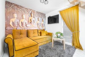 a living room with a yellow couch and a painting at Słoneczne Domki in Rewal