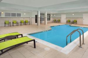 a pool with chairs and tables in a hotel room at SpringHill Suites Alexandria in Alexandria