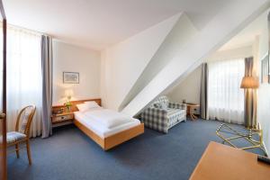 a bedroom with a bed and a chair in a room at Hotel & Restaurant zum Ritter in Attendorn