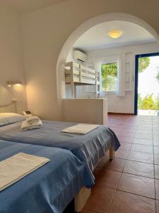 two beds in a room with a kitchen in the background at Paros Philoxenia in Chrissi Akti